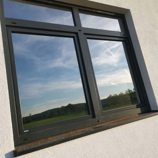 Moderne Glasfassade eines Bürogebäudes in Geretsried mit maßgeschneiderter Flachglas-Sonnenschutzfolie für effektiven Hitzeschutz und UV-Schutz von c&w – das Werbezentrum.