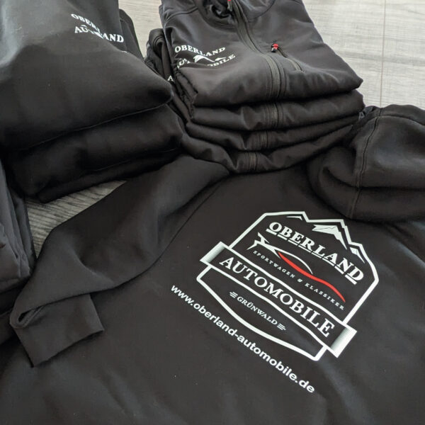 Hochwertig bedrucktes schwarzes Polo-Shirt mit dem Logo von Oberland Automobile, professionell veredelt durch C&W - das Werbezentrum in Geretsried.