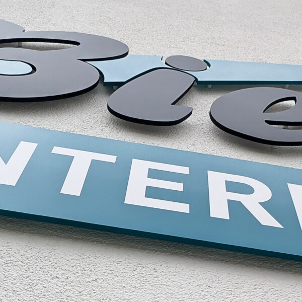 3-farbige 3D Fräsbuchstaben als Firmenlogo an einer modernen Außenfassade, professionell montiert von c&w - das Werbezentrum in Geretsried.